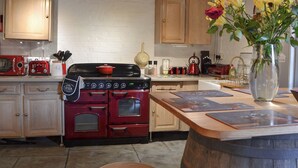 A kitchen with wooden beams, a red stove, and a vase with flowers on the island. - 2 bedroom accommodation in Shobley, Ringwood (Shobley, Ringwood)