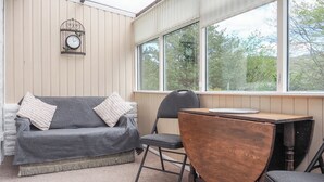 Une pièce chaleureuse avec un canapé gris, un bureau en bois et une chaise. Une horloge murale est fixée au mur.