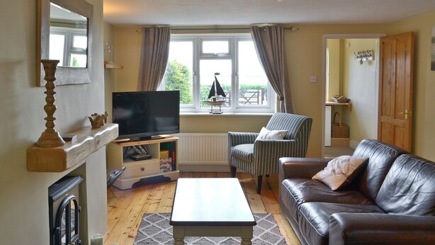 Ein Wohnzimmer mit Fernseher, einem gestreiften Sessel, einem Ledersofa und einem Kamin.