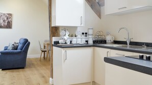 A compact kitchen with white cabinets, a black countertop, and a wooden ceiling beam. - 1 bedroom accommodation in Six Ashes, near Bridgnorth (Six Ashes, near Bridgnorth)