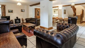 Ein großzügiger Wohnbereich mit Ledersofas, einem Holztisch und einem Essbereich mit Holzkästen.