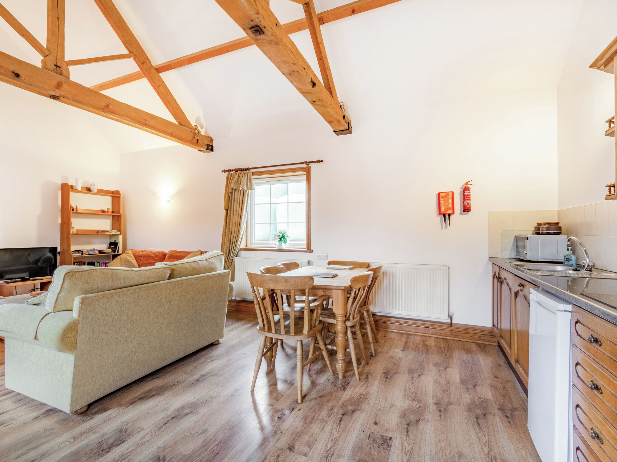 Una sala de estar acogedora con sofá, una mesa de comedor con sillas y una zona de cocina con fregadero y armarios.