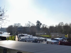A marina with boats docked, a clear sky, and trees in the background.