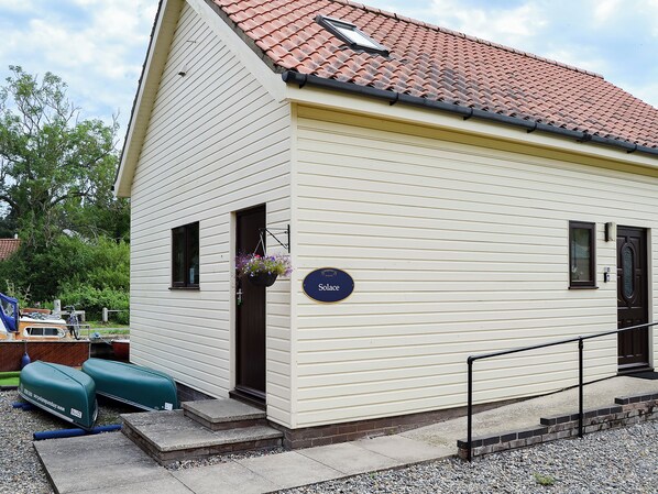 A small, single-story building with a red-tiled roof, a dark brown door, and a small window.