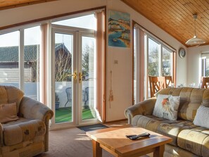 A living room with two sofas, a coffee table, and a painting on the wall. - 3 bedroom accommodation in Haverigg, near Millom (Haverigg, near Millom)