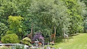 A garden with various plants, a fountain, and giraffes.