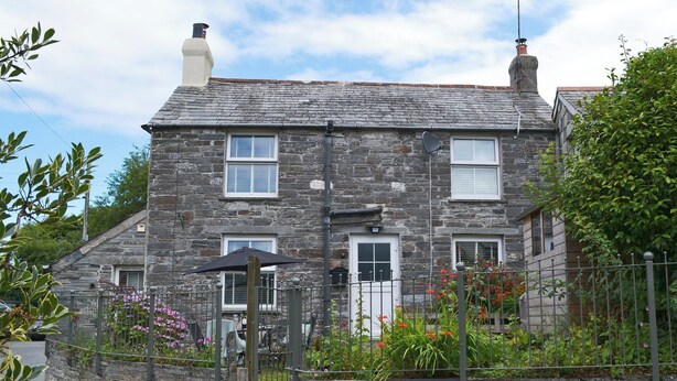 A stone house with a sloped roof, multiple windows, and a garden with flowers and plants. - 2 bedroom accommodation in Trewalder, near Wadebridge (Trewalder, near Wadebridge)