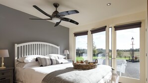 A bedroom with a bed, a ceiling fan, a nightstand with a lamp, and a view of the outdoors through a door. - 1 bedroom accommodation in South Elkington, near Louth (South Elkington, near Louth)