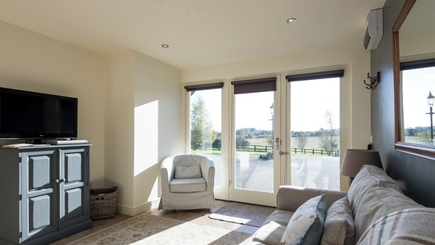 A living room with a television, a sofa, a chair, and a large window with a view of the outside. - 1 bedroom accommodation in South Elkington, near Louth (South Elkington, near Louth)