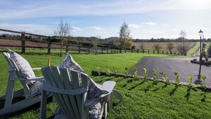 A grassy outdoor area with a wooden fence, a paved path, and a lamp post. - 1 bedroom accommodation in South Elkington, near Louth (South Elkington, near Louth)