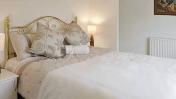 Una cama bien hecha con almohadas estampadas con motivos florales y una colcha blanca.