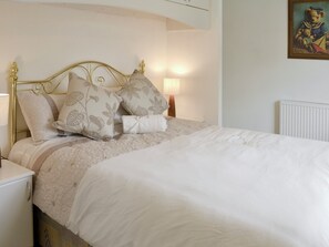 A neatly made bed with floral-patterned pillows and a white comforter.