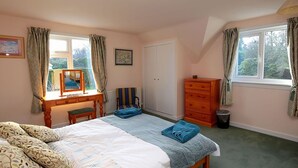 A bedroom with a bed, a dresser, a chair, a desk with a mirror, and two windows with curtains. - 4 bedroom accommodation in Gatehouse of Fleet, Kirkcudbright (Gatehouse of Fleet, Kirkcudbright)
