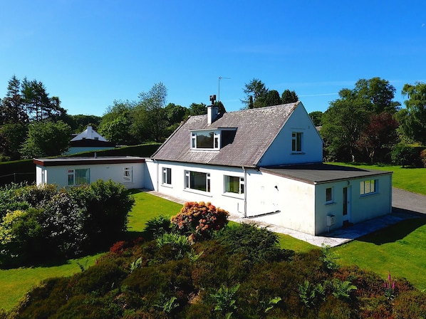 A two-story house with a sloped roof, a visible chimney, and a well-maintained lawn.