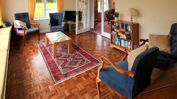 A cozy living room with wooden flooring, a coffee table, two armchairs, a bookshelf, and a television. - 4 bedroom accommodation in Gatehouse of Fleet, Kirkcudbright (Gatehouse of Fleet, Kirkcudbright)