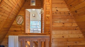 Un intérieur en bois avec un plafond en pente, une petite fenêtre et un radiateur.