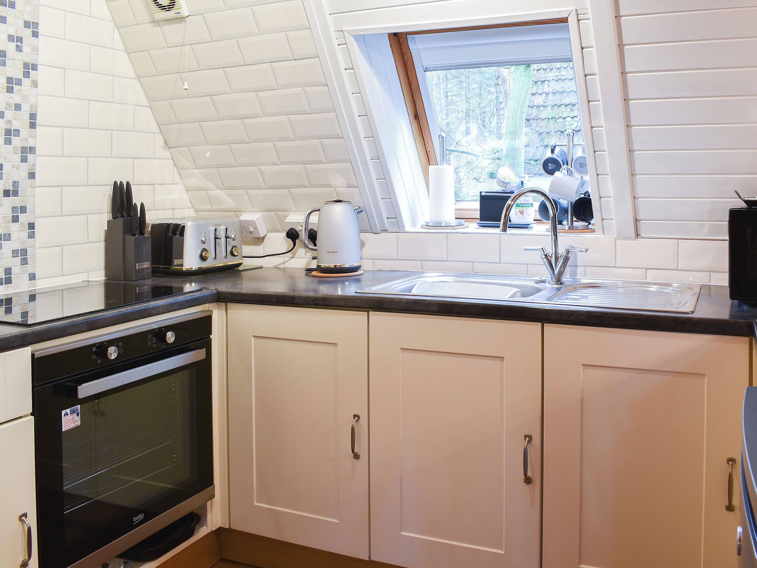 A kitchen with a built-in oven, a coffee maker, and a sink.