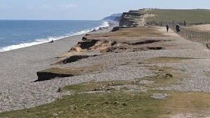 Une promenade côtière avec un sentier rocailleux, une zone herbeuse et une vue sur la mer.