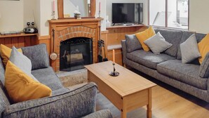 A living room with a fireplace, two sofas, a coffee table, a TV, and a large window. - 3 bedroom accommodation in Chickerell, near Weymouth (Chickerell, near Weymouth)