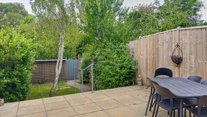 A patio with a table and chairs, surrounded by a wooden fence and greenery. - 3 bedroom accommodation in Chickerell, near Weymouth (Chickerell, near Weymouth)