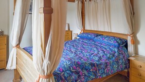A four-poster canopy bed with a floral bedspread, wooden headboard, and matching curtains. - 3 bedroom accommodation in Chickerell, near Weymouth (Chickerell, near Weymouth)