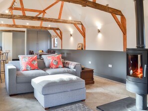 A living room with a sofa, ottoman, and a wood-burning stove.