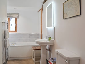 A bathroom with a bathtub, a sink, a toilet, a window, and a mirror.
