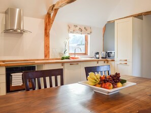 A kitchen with a wooden table, chairs, a fruit bowl, and a window. - Chiddock Cottage - UKC2540 (Midgham, near Fordingbridge)