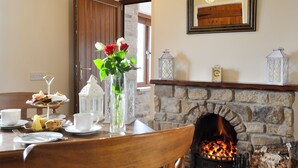 A dining area with a stone fireplace, a wooden table set with plates, cups, and a vase of flowers. - 1 bedroom accommodation in Baldersdale, near Barnard Castle (Baldersdale, near Barnard Castle)