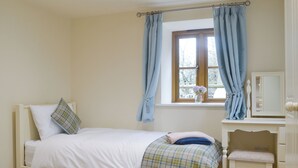 Ein Schlafzimmer mit einem Bett, einem Schreibtisch und einem Fenster mit Vorhängen.