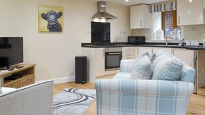 Eine moderne Küche mit Fernseher, Sofa und einem Gemälde an der Wand.