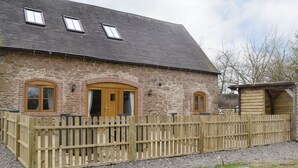 Ein Steinhaus mit Holzzaun, zwei Türen und einer kleinen Holzhütte.