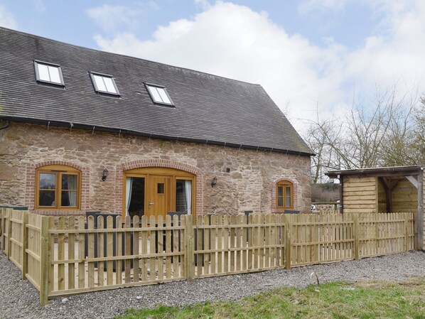 A stone building with a wooden fence, two doors, and a small wooden structure.