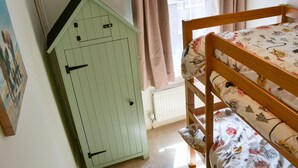 A room with a bunk bed, a green cabinet, a radiator, and a window with curtains. - 3 bedroom accommodation in Cromer (Cromer)