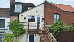 A two-story house with a wooden staircase leading to a small porch. - 3 bedroom accommodation in Cromer (Cromer)