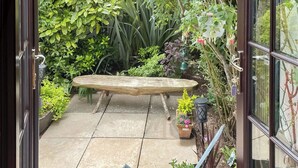 Eine Gartenpatio mit einer Holzbank, Blumentöpfen und einem Metallstuhl.