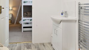 Une chambre avec un lit superposé, un lavabo blanc et un radiateur.