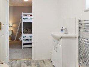 A room with a bunk bed, a white sink, and a radiator. - 2 bedroom accommodation in Pyworthy, near Holsworthy (Pyworthy, near Holsworthy)