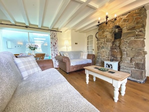 A cozy living room with a stone wall, a wooden coffee table, and a sofa with a plaid throw. - 2 bedroom accommodation in Pyworthy, near Holsworthy (Pyworthy, near Holsworthy)