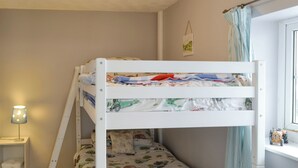 A bunk bed with a lower bunk, a bedside table with a lamp, a small shelf with a basket, and a window with curtains. - 2 bedroom accommodation in Pyworthy, near Holsworthy (Pyworthy, near Holsworthy)