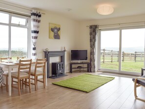 A living room with a fireplace, television, dining table, and chairs. - 1 bedroom accommodation in Hapton (Hapton)