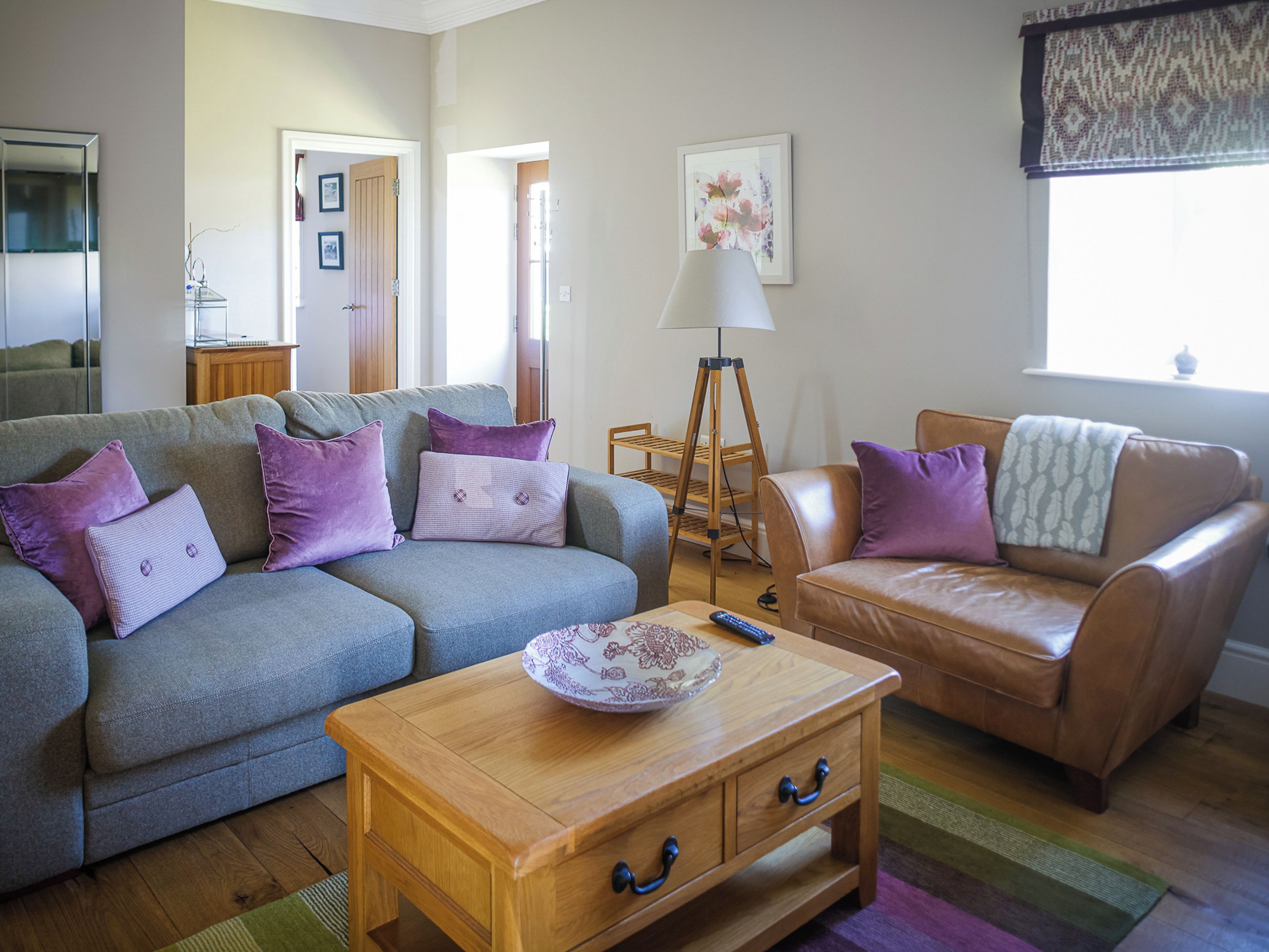 A living room with a grey sofa, a brown leather chair, a wooden coffee table, and a floor lamp.