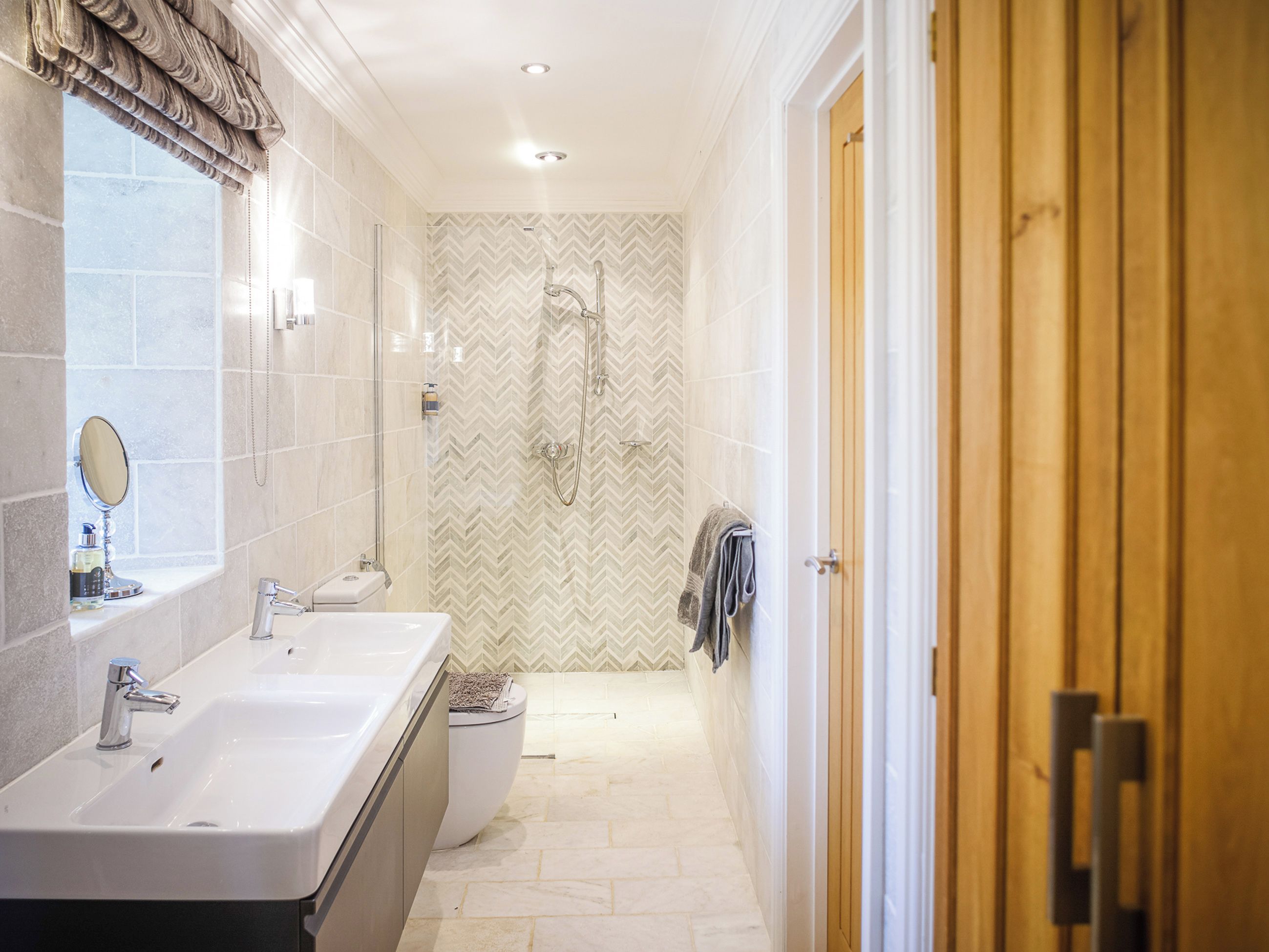 A bathroom with a double sink, a mirror, a shower, and a towel rack.