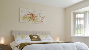 A bedroom with a bed, bedside tables, a window, and a floral painting on the wall. - 1 bedroom accommodation in Broadstone, near Bournemouth (Broadstone, near Bournemouth)