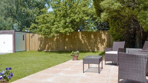A patio with wicker furniture, a small potted plant, and a shed in a backyard. - 1 bedroom accommodation in Broadstone, near Bournemouth (Broadstone, near Bournemouth)