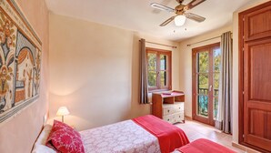 A bedroom with two beds, a ceiling fan, a wooden dresser, and a window with curtains. - Fantastic Villa "Calima" with Sea Views, Loggia, Air Conditioning, and Wi-Fi (S'Estany den Más)