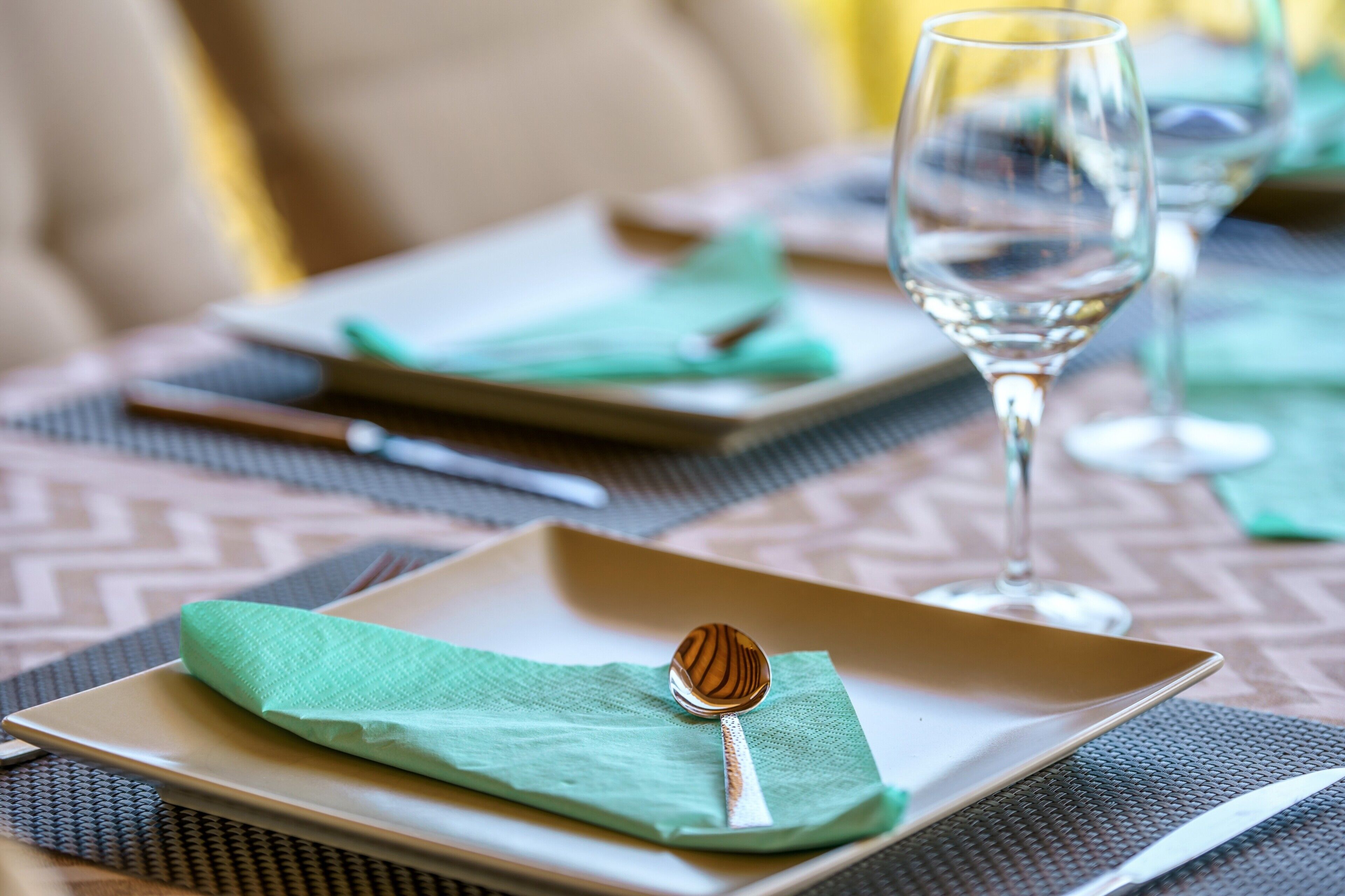 Ein gedeckter Tisch mit Teller, Löffel, Serviette und Glas.