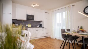 A modern kitchen with white cabinets, a microwave, and a dining area with a wooden table and chairs.