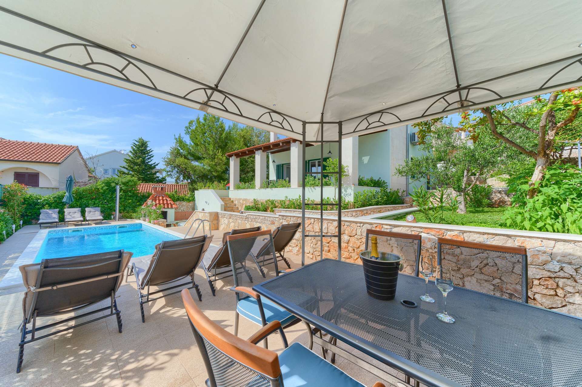 Un espace extérieur avec une piscine, des chaises longues et une table, le tout entouré de murs en pierre et de verdure.