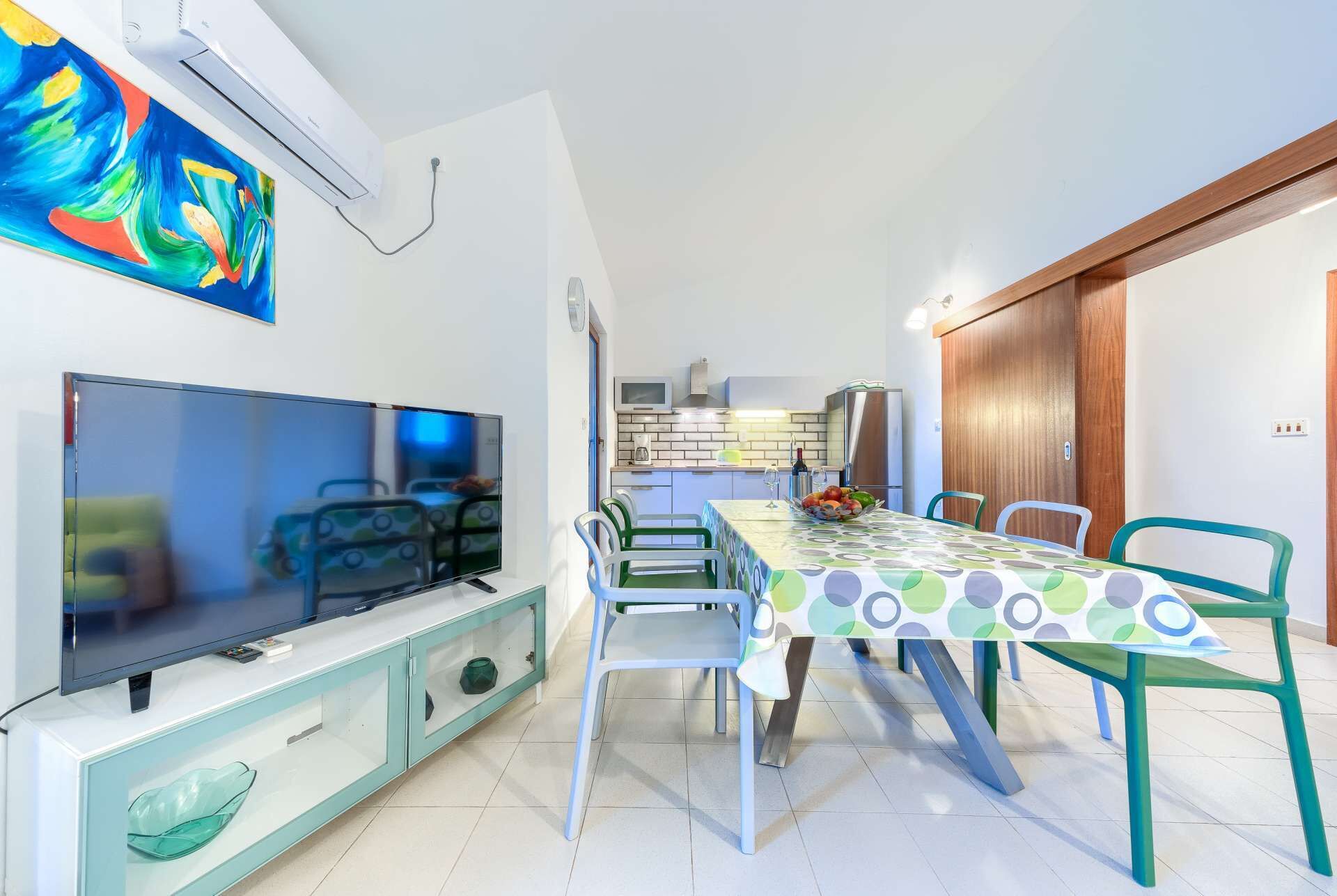 A compact living space with a dining area, kitchenette, and a TV.
